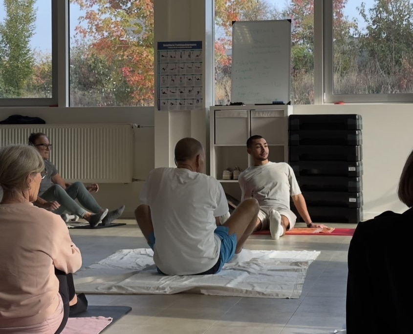 Rehasport-Gruppe mit Trainer David auf Matten im Kursraum